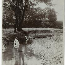 Girl standing in creek, playing with other boy